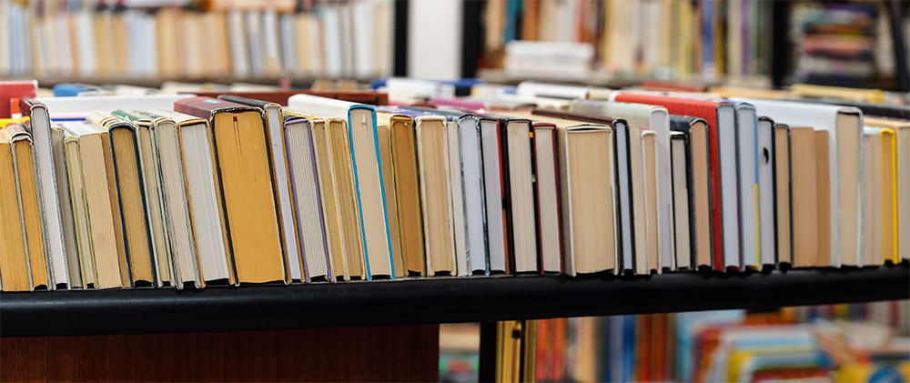 Row of many old used books displayed at local antiquarian booksh